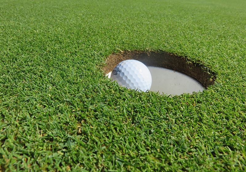 En golfboll på väg ner i ett banhål.