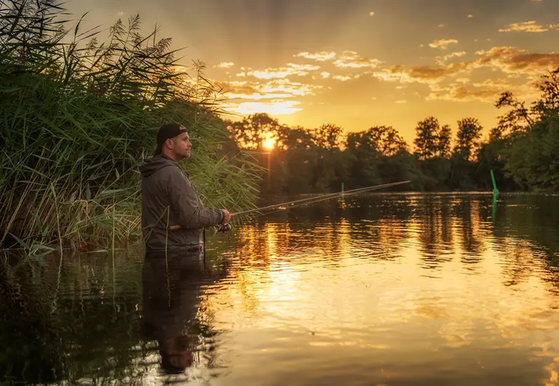 En man står i floden Lagan och fiskar i soluppgången.